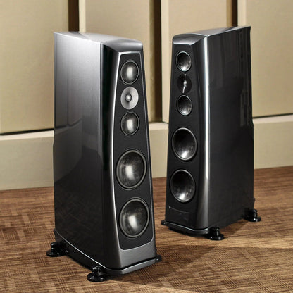 Pair of black Rockport Technology Lyra speakers on a wooden floor with beige walls in the background